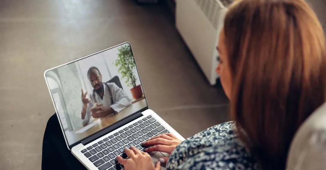 A person talks to a doctor though a video chat on her laptop.