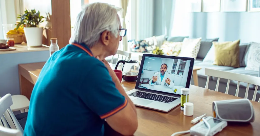 A person talking to a doctor via a video chat on his laptop.