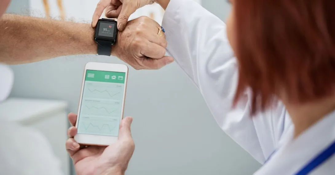 Doctor showing patient how to synchronize health app in smartphone and smartwatch