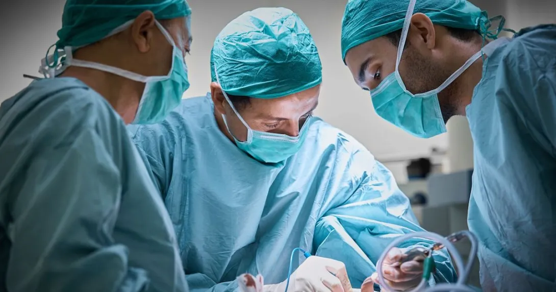 Surgeons in an operating room wearing scrubs and operating on a patient
