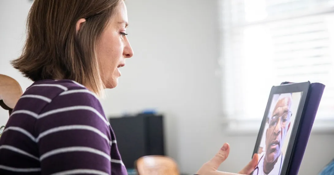 Person sitting at a desk while talking to a healthcare provider on their computer