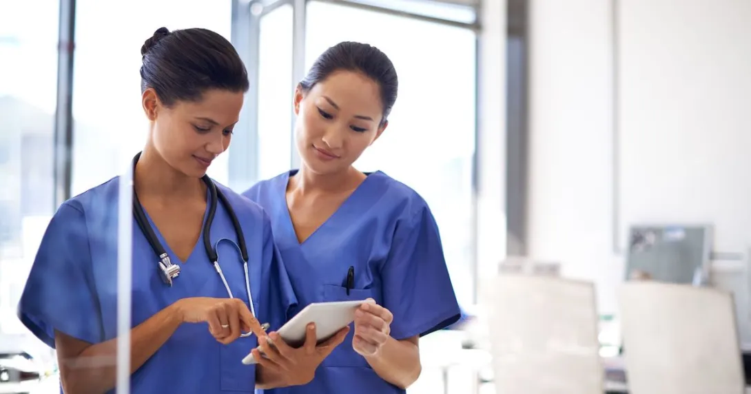 Two healthcare providers looking at a tablet