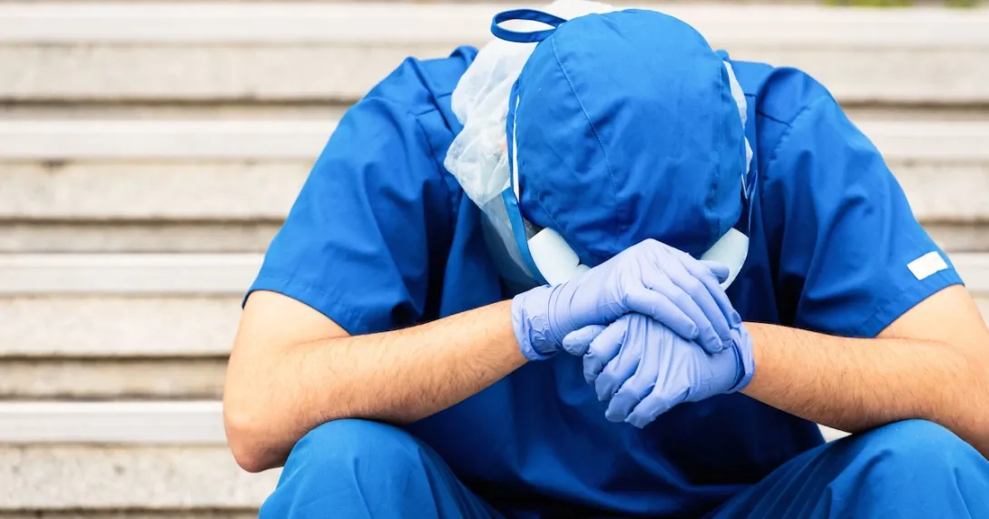 Healthcare provider sitting with their head in their hands