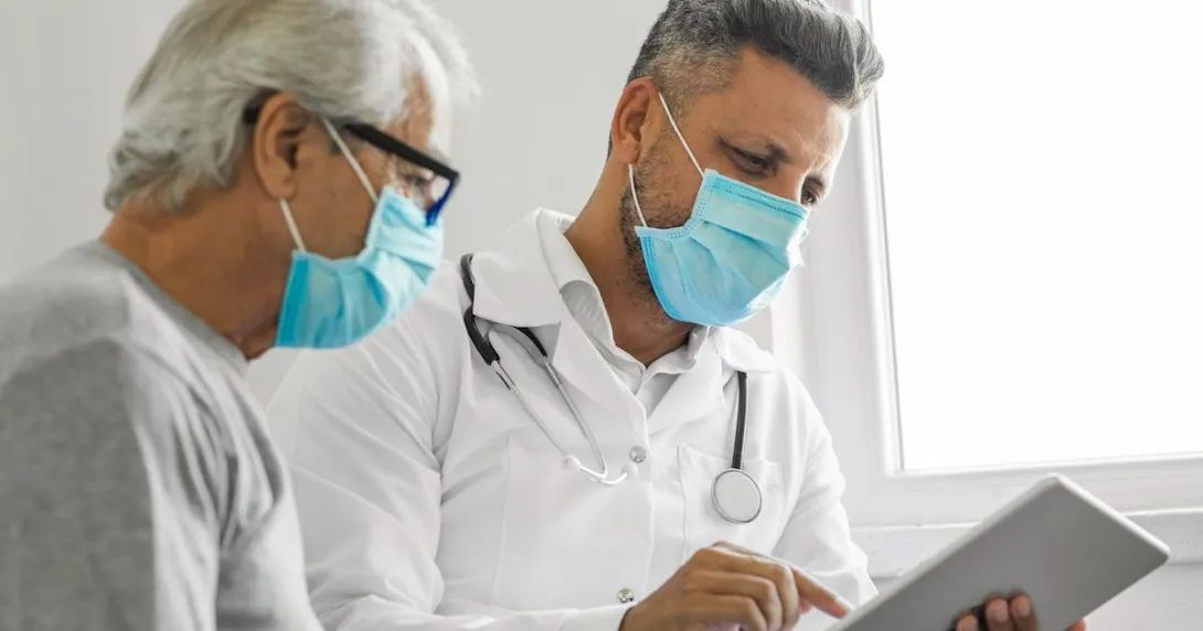 Healthcare provider sitting with a patient while looking at a tablet