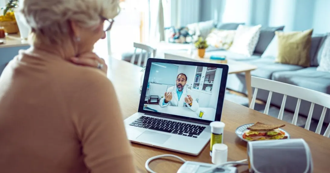 Person sitting at computer talking with person in lab coat
