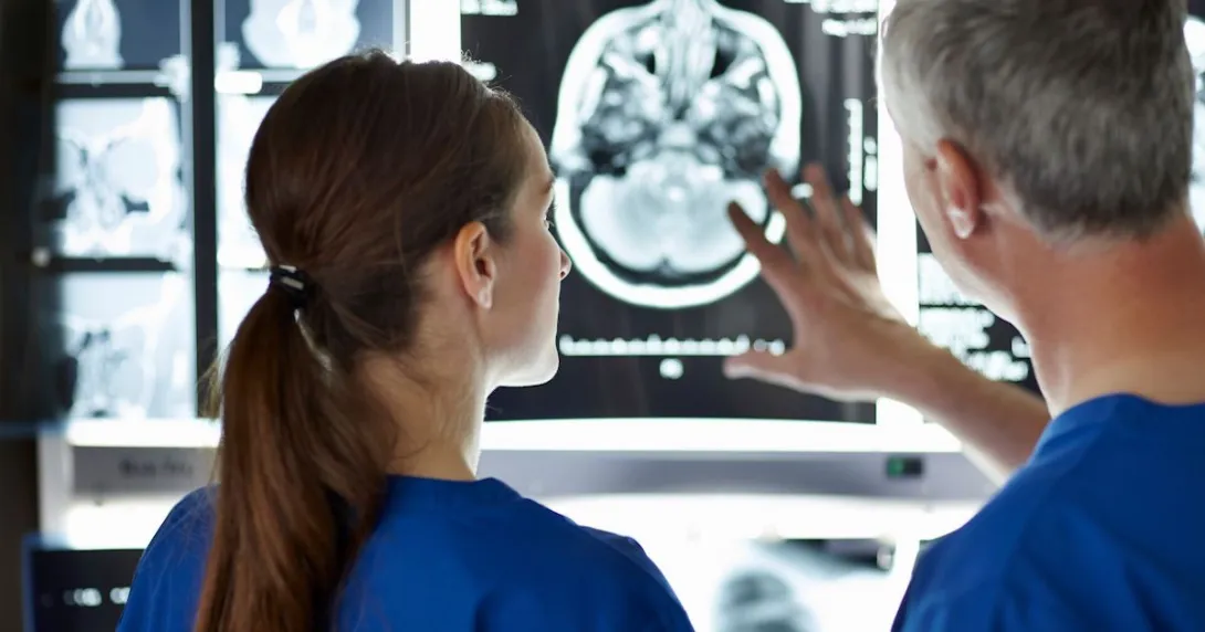 Two healthcare providers standing in front and evaluating brain imaging scans