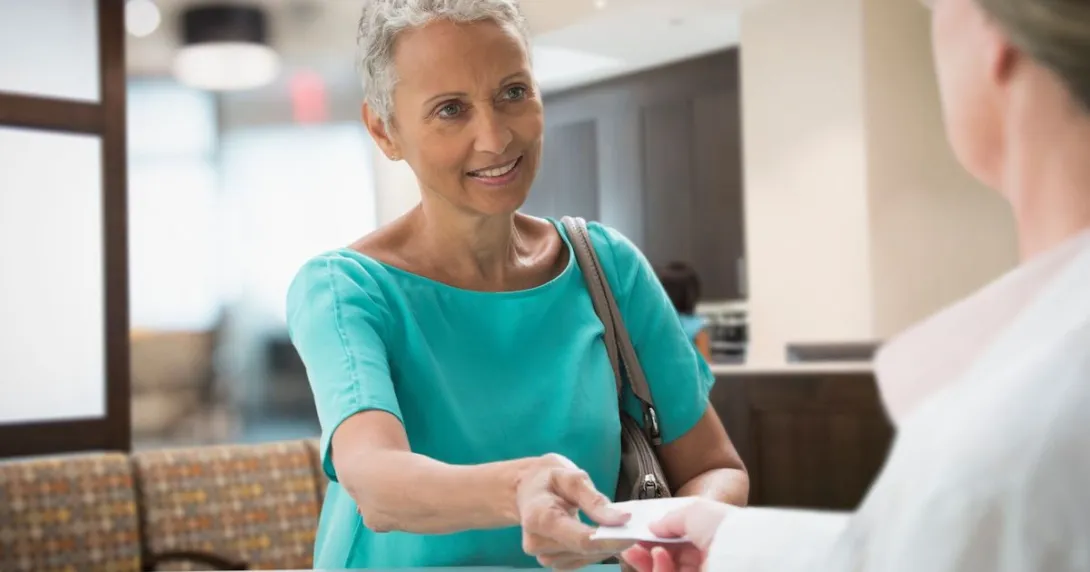 Person handing a piece of paper to a pharmacist