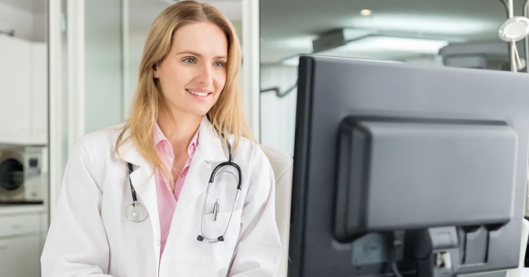 A doctor checking a patient's medical record on a desktop computer