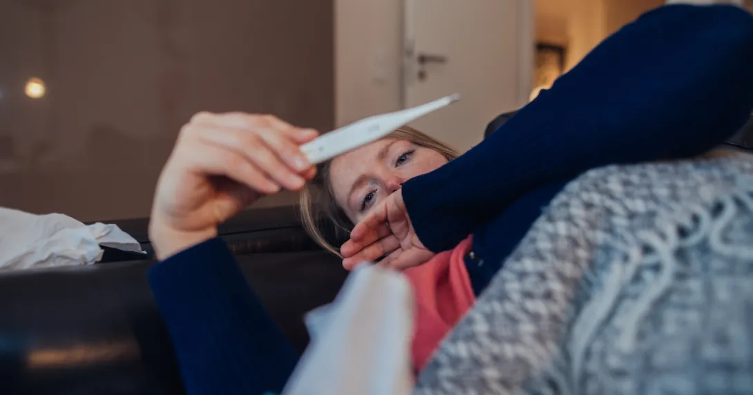 A sick person looking at a thermometer